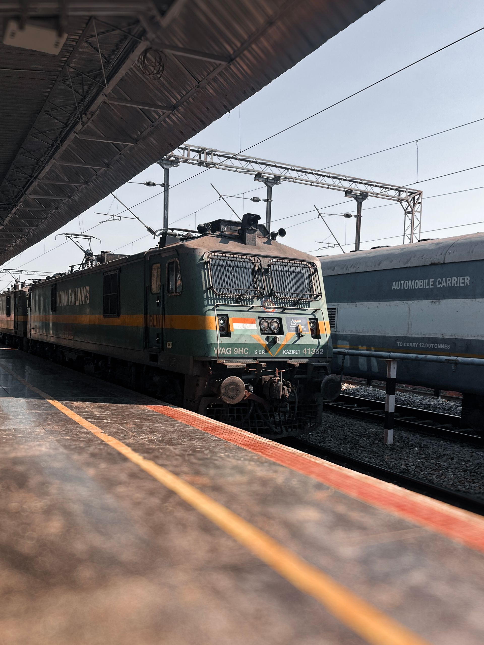 A classic green and yellow locomotive at the bustling Bengaluru railway station in India.